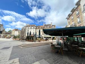 a city square with tables and chairs and an umbrella at Sweethost - L'Amazone - T2 Proche Gare & Disneyland in Lagny