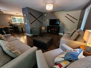 a living room with couches and a large clock on the wall at The Hidden Porch at Sir Sam's (hot tub & sauna) in Haliburton