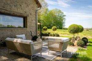 an outdoor patio with wicker chairs and a window at The Louis Aragon Cottage Exceptional Elegance in Nexon