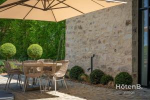 a table and chairs with an umbrella on a patio at The Louis Aragon Cottage Exceptional Elegance in Nexon