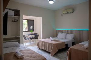 um quarto de hotel com duas camas e uma mesa em Pousada Sol da Enseada Guarujá no Guarujá