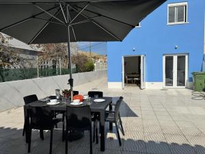 Ein schwarzer Tisch und Stühle mit einem Sonnenschirm auf einer Terrasse in der Unterkunft Caparica Villa blue beach in Costa da Caparica