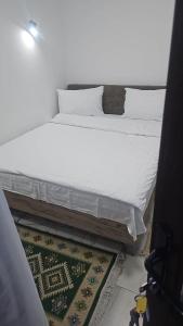 uma cama com lençóis brancos e almofadas num quarto em Casa Rustica Cernica em Cernica
