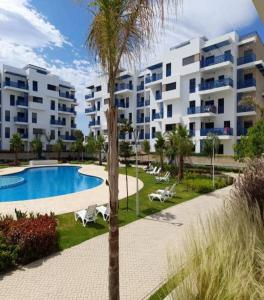een appartementencomplex met een zwembad en een palmboom bij Residence Costa-Mar in Martil