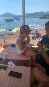 un niño pequeño sentado en una mesa de picnic en la playa en Apartments Langust en Sveti Stefan