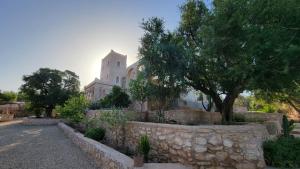a church with a stone wall in front of a building at Dar Ez-zine in Ounara