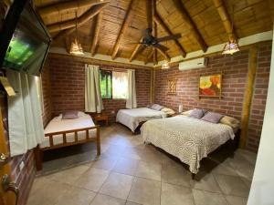 1 dormitorio con 2 camas en una pared de ladrillo en Las Cabañas, en Olón