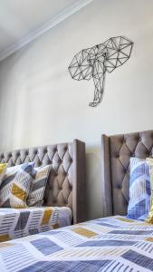 a bedroom with a bed with a headboard and aigraph at Impeccable Apartment in Victoria Falls 128 TheYard in Victoria Falls