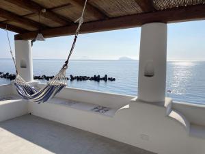 a porch with a hammock and a view of the ocean at Villa Maris - accesso diretto alla spiaggia in Santa Marina Salina