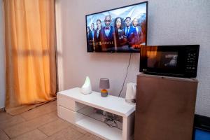 a living room with a tv and a white table with a microwave at Studio cosy et agréable in Lomé
