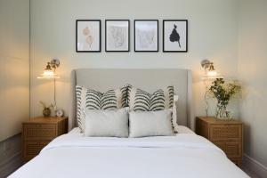 - une chambre avec un lit blanc et trois photos sur le mur dans l'établissement The Manor Gardens Retreat - Captivating 1BDR Flat with Terrace, à Londres