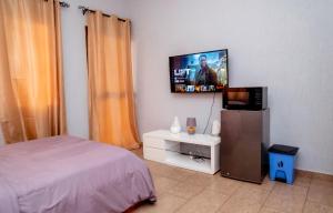 a bedroom with a bed and a flat screen tv at Studio cosy et agréable in Lomé