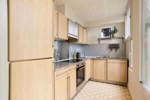 eine Küche mit Holzschränken und einem Kühlschrank in der Unterkunft The Manor Gardens Retreat - Captivating 1BDR Flat with Terrace in London