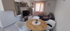 een woonkamer met een houten tafel en witte stoelen bij Apartment Olive in Kaštela