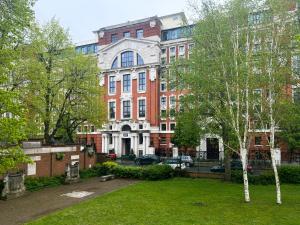 un grand bâtiment en briques avec un parc en face dans l'établissement The Manor Gardens Retreat - Captivating 1BDR Flat with Terrace, à Londres