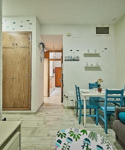 ein Wohnzimmer mit einem Tisch und blauen Stühlen in der Unterkunft The Sailors House Ha in Cádiz