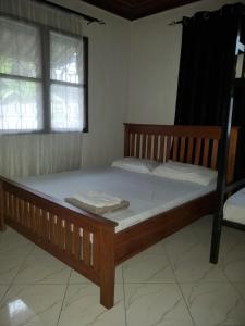 uma cama de madeira num quarto com 2 janelas em Nest Haven Homestay-Hostel em Dar es Salaam