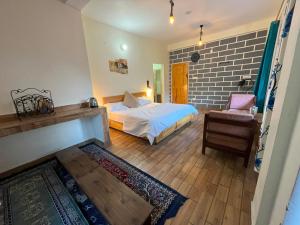 a bedroom with a bed and a chair and a brick wall at Rishi Villa in Manāli