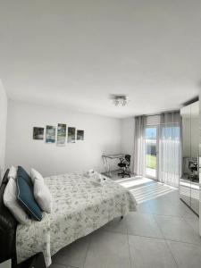 a white bedroom with a bed and a window at Terme Apartment Levico in Levico Terme