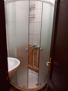 a shower with a glass door next to a sink at Hostel Wien in Novi Pazar
