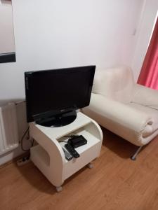 - un salon avec une télévision et un canapé blanc dans l'établissement Hostel Wien, à Novi Pazar