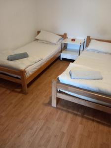 two twin beds in a room with a wooden floor at Hostel Wien in Novi Pazar