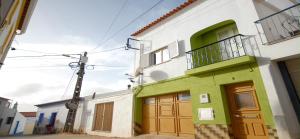 Happy Hostel Sagres في Raposeira: مبنى أخضر وبيضاء مع شرفة