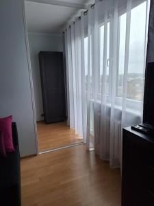 Pokój z lustrem i oknem z białymi zasłonami w obiekcie Turkusowa Apartament w Szczecinie