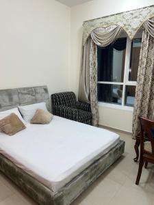 a bed in a room with a chair and a window at R2)Sweet Home fantastic city and sea view at beachإطلالة رائعة على المدينة والبحر على الشاطئ in Ajman 