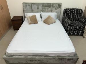a white bed with two pillows and a chair at R2)Sweet Home fantastic city and sea view at beachإطلالة رائعة على المدينة والبحر على الشاطئ in Ajman 