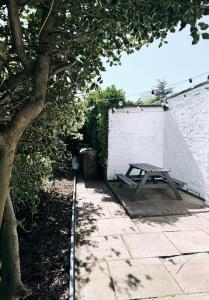 a picnic table sitting next to a white brick wall at Spacious Victorian Birkdale Apartment with Garden in Southport