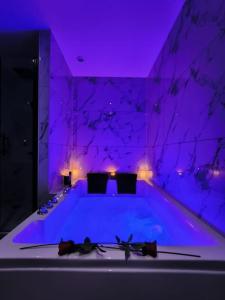 een paarse kamer met een bad met verlichting bij LOVE ROOM - Amour Chic et Intime in Montbrison