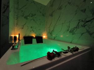 a bath tub with green water in a room at LOVE ROOM - Amour Chic et Intime in Montbrison