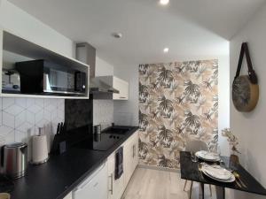 a kitchen with a black counter top and a table at LOVE ROOM - Amour Chic et Intime in Montbrison
