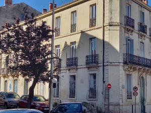 a large white building with cars parked in front of it at Appartement cosy 60m², proche gare St Roch et centre. in Montpellier