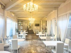タルクイーニアにあるHotel La Torracciaの白いテーブルと椅子、シャンデリアのあるレストラン