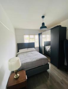 een slaapkamer met een bed, een tafel en een lamp bij Inviting 4-Bed House in Leeds in New Malden