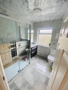 uma casa de banho com uma cabina de duche em vidro e um WC. em Inviting 4-Bed House in Leeds em New Malden