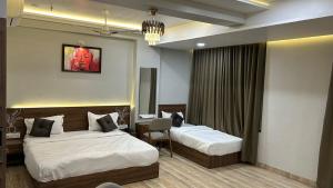 a hotel room with two beds and a desk at Hotel Holiday Icon in Dwarka