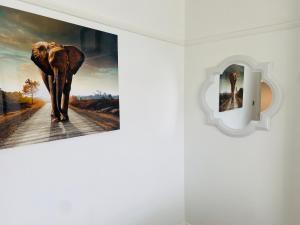 een olifant die over een weg loopt gedrukte foto op een muur bij Inviting 4-Bed House in Leeds in New Malden