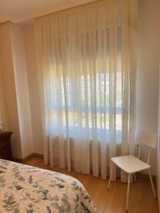 a bedroom with a bed and a window with a chair at Habitaciones De Lujo Con Hermosas Vistas A La Cuidad in Burgos
