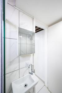 uma casa de banho branca com um lavatório e um espelho em 46 LOFT TRIPLO · Mini apartamento em Metrô Jabaquara e EXPO em São Paulo