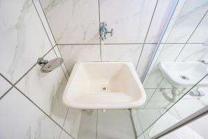 a white sink in a white tiled bathroom at 46 LOFT TRIPLO · Mini apartamento em Metrô Jabaquara e EXPO in São Paulo