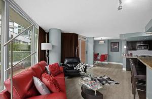 a living room with a red couch and a kitchen at Luxury Designer Condo In The Heart Of Downtown - Best Location! in Vancouver