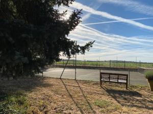 un banco sentado al lado de una pista de tenis en Le Montoir en Faverolles