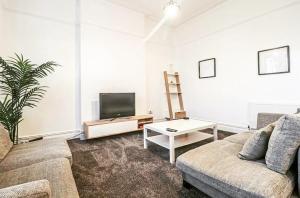 a living room with a couch and a tv at Spacious Victorian Birkdale Apartment with Garden in Southport