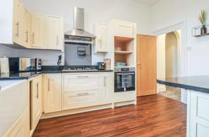 Una cocina con gabinetes blancos y electrodomésticos negros. en Spacious Victorian Birkdale Apartment with Garden, en Southport