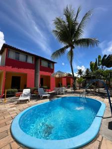 a pool in front of a house with a palm tree at Pousada Flor de Porto in Porto De Galinhas