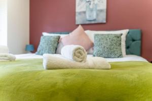 a bedroom with two towels on a green bed at Hayes Home - Easy links to LHR and London in Northolt