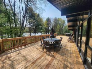 een terras met een tafel en stoelen op een dek bij Red Cedar Chalet on Brady Lake in Hindon Hill